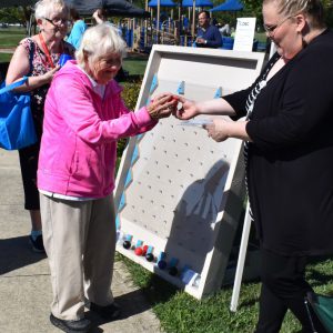 A lady receives a stress ball as a prize for playing Plinko